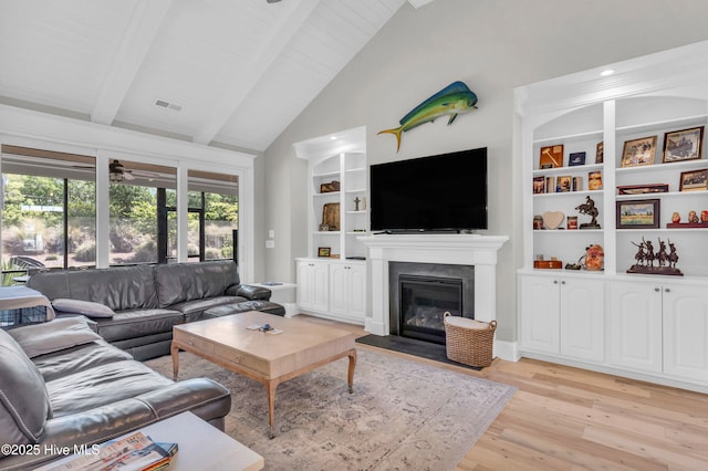 living room featuring light wood-style floors, a fireplace with flush hearth, built in features, and beamed ceiling