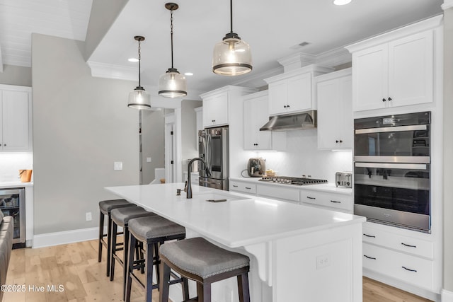 kitchen featuring a sink, under cabinet range hood, wine cooler, stainless steel appliances, and recessed lighting