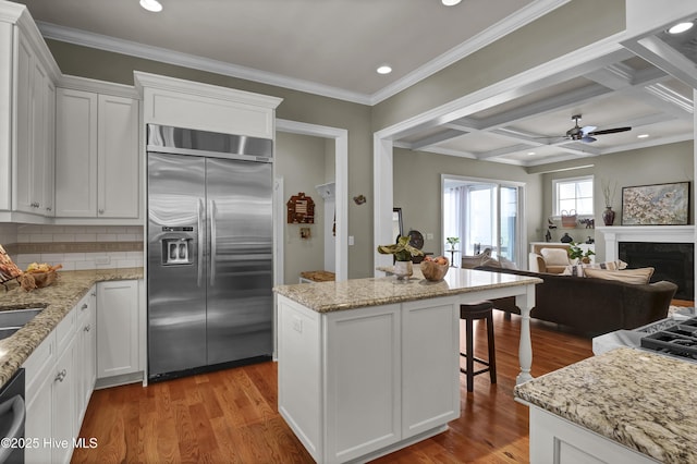 kitchen featuring built in fridge, open floor plan, wood finished floors, white cabinets, and recessed lighting