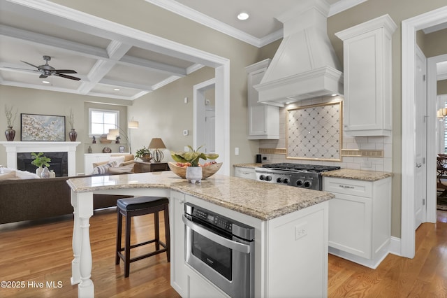 kitchen featuring premium range hood, oven, open floor plan, white cabinets, and recessed lighting