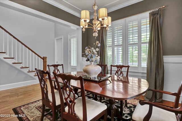 dining area featuring wood finished floors, a chandelier, crown molding, and stairs