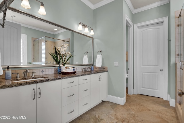 bathroom featuring a stall shower, baseboards, double vanity, and crown molding