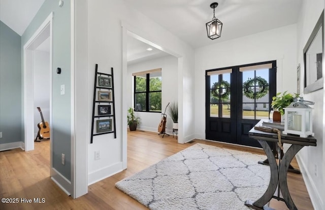 entrance foyer with baseboards, french doors, and light wood-type flooring