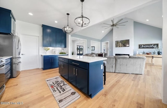 kitchen featuring a kitchen island, blue cabinets, light wood-type flooring, light countertops, and ceiling fan with notable chandelier