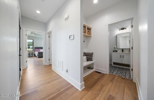 hallway with recessed lighting, baseboards, visible vents, and light wood finished floors