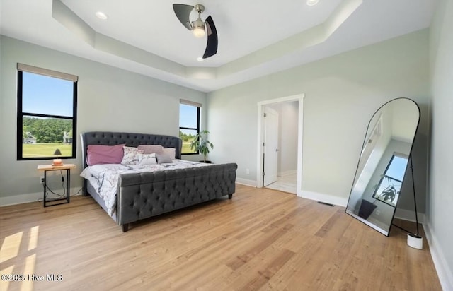 bedroom featuring visible vents, baseboards, light wood-type flooring, recessed lighting, and a raised ceiling