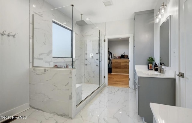 bathroom featuring vanity, marble finish floor, a marble finish shower, and a walk in closet