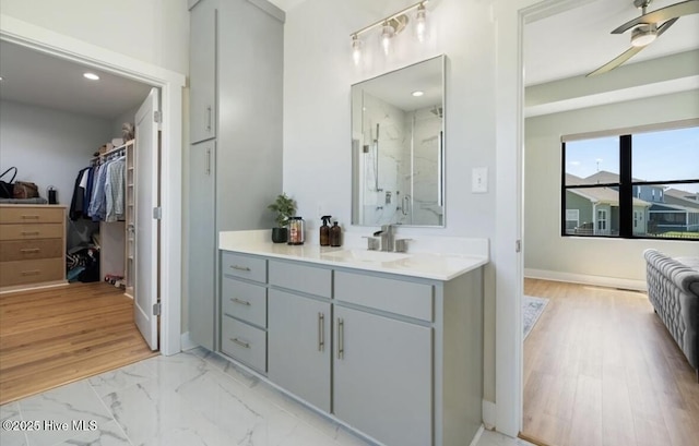 full bathroom with a walk in closet, ceiling fan, vanity, a marble finish shower, and recessed lighting