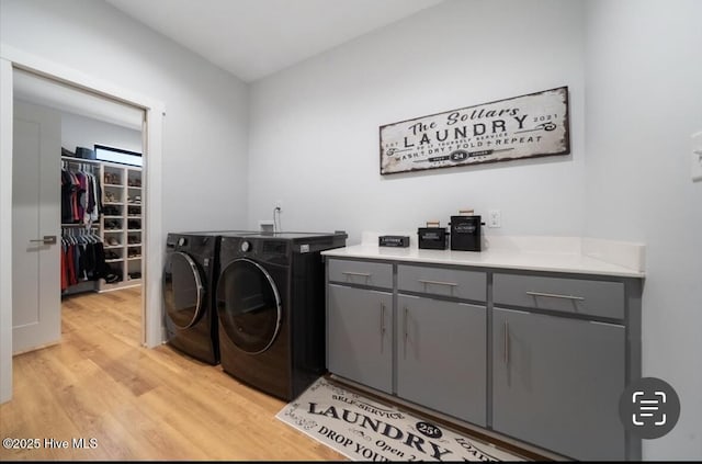 washroom featuring light wood-type flooring, cabinet space, and washing machine and clothes dryer