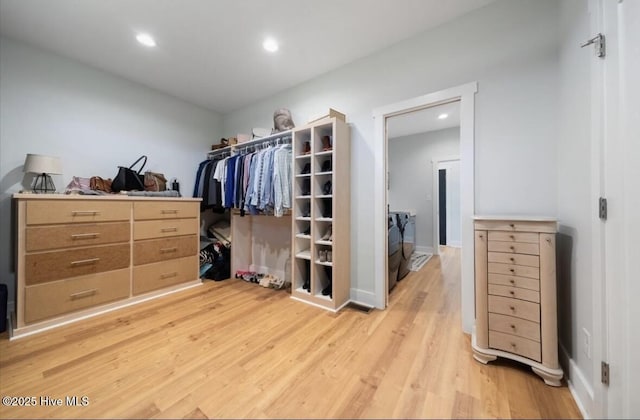 walk in closet with light wood-style floors