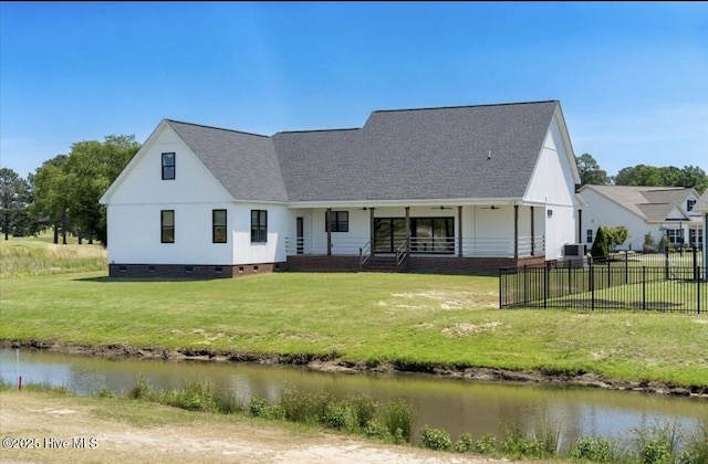 rear view of property featuring fence, covered porch, roof with shingles, crawl space, and a yard
