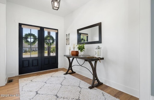 entrance foyer featuring french doors, baseboards, wood finished floors, and visible vents