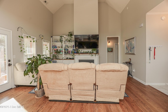 living area featuring visible vents, a fireplace, wood finished floors, and high vaulted ceiling