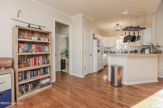 kitchen with crown molding, white fridge with ice dispenser, wood finished floors, and white cabinetry