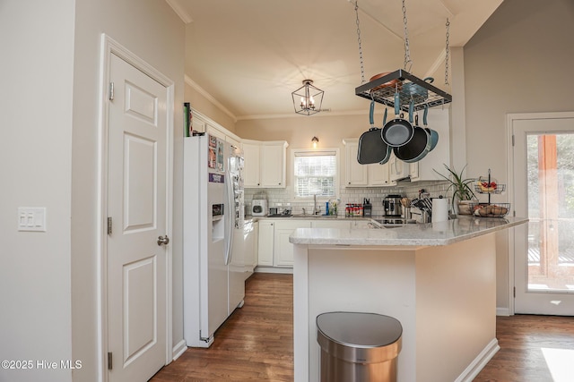kitchen with decorative backsplash, dark wood-style flooring, a peninsula, ornamental molding, and a sink