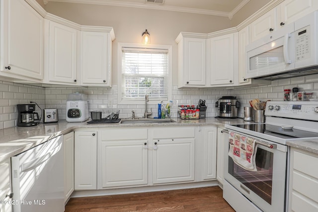 kitchen featuring a sink, crown molding, backsplash, and white appliances