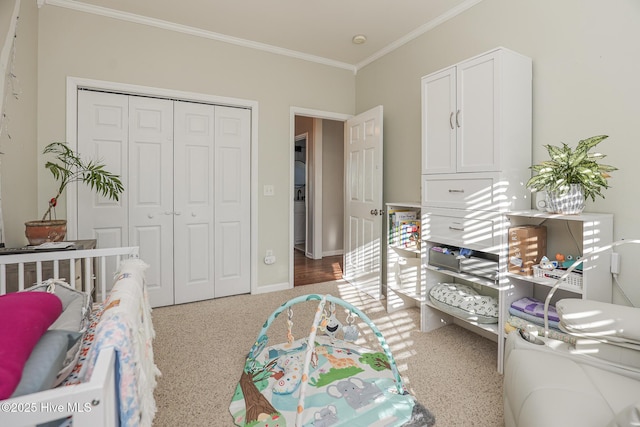 carpeted bedroom featuring crown molding, baseboards, and a closet