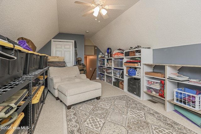 living area featuring carpet flooring, a ceiling fan, a textured ceiling, and lofted ceiling