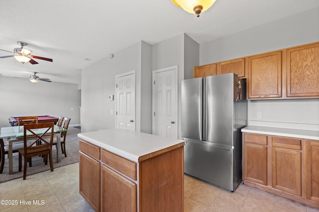 kitchen with freestanding refrigerator, a ceiling fan, a kitchen island, and light countertops