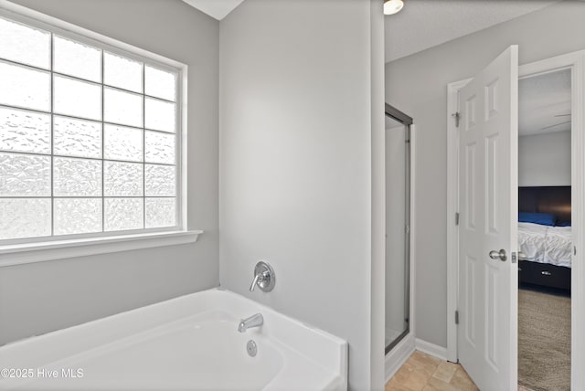 bathroom with a bath, stone finish flooring, ensuite bath, and a shower stall