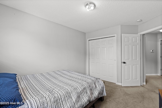 carpeted bedroom with a textured ceiling, baseboards, and a closet