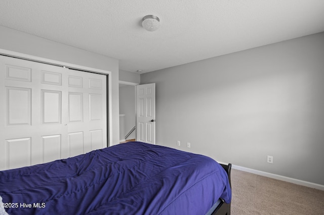 bedroom with a textured ceiling, baseboards, carpet, and a closet