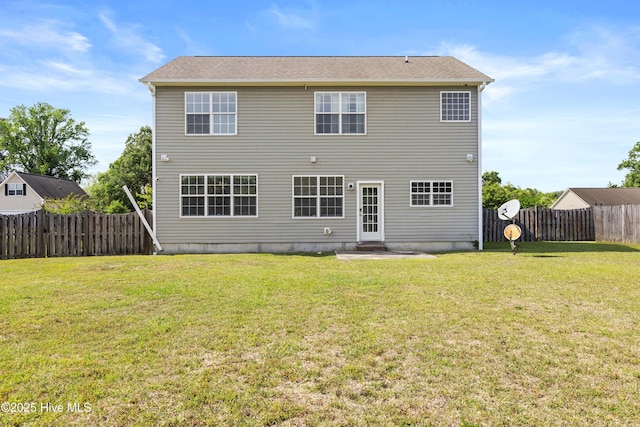 rear view of house with a lawn, a fenced backyard, and entry steps