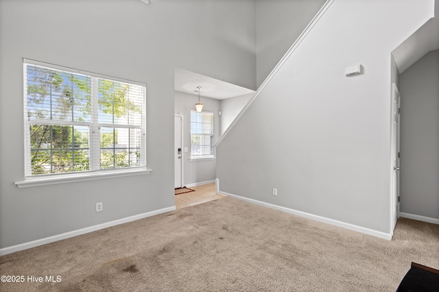 unfurnished living room featuring baseboards and carpet flooring
