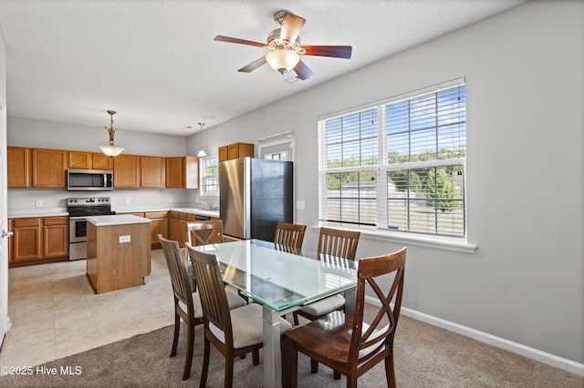 dining area with light carpet, a textured ceiling, a ceiling fan, baseboards, and light tile patterned floors