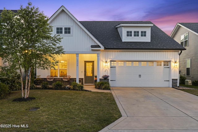 view of front of home with a garage, board and batten siding, a porch, a lawn, and driveway