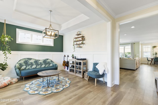 living room with ornamental molding, a decorative wall, wood finished floors, and a chandelier