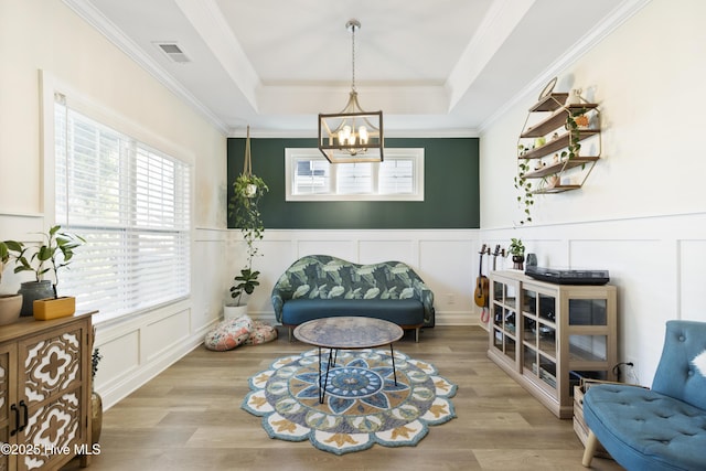 living area with visible vents, a wainscoted wall, a decorative wall, and an inviting chandelier