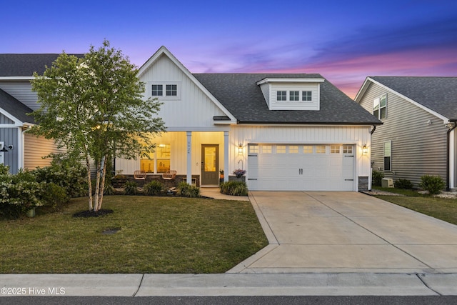 view of front of home with a garage, board and batten siding, covered porch, and a front yard
