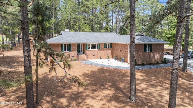 180 Lancashire Ln, West End, NC 27376 - view of front of home featuring roof with shingles, a chimney, and brick siding