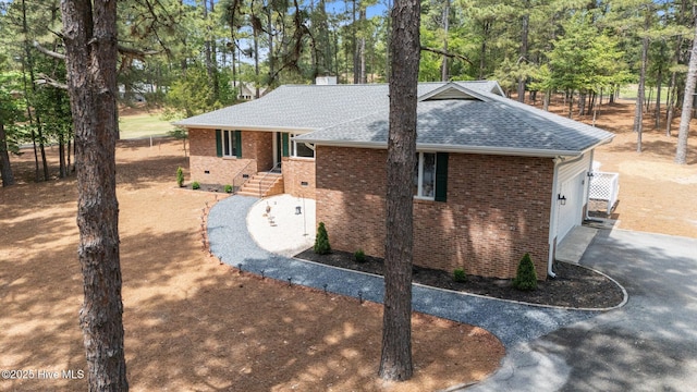 180 Lancashire Ln, West End, NC 27376 - view of side of property featuring a garage, a chimney, brick siding, a shingled roof, and driveway