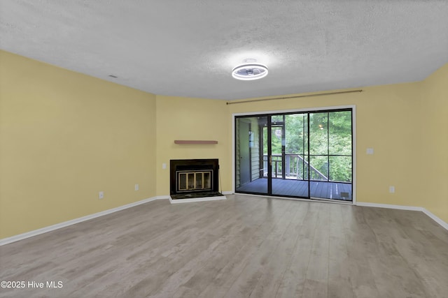 10165 Creekside Dr SE Apt 1, Leland, NC 28451 - unfurnished living room featuring a textured ceiling, wood finished floors, baseboards, and a glass covered fireplace