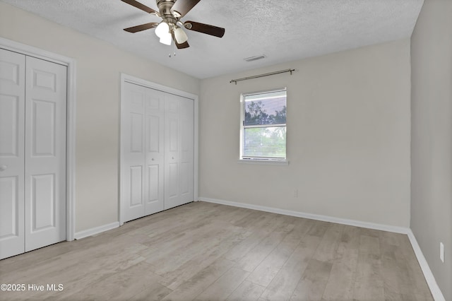 10165 Creekside Dr SE Apt 1, Leland, NC 28451 - unfurnished bedroom featuring wood finished floors, two closets, a textured ceiling, baseboards, and ceiling fan