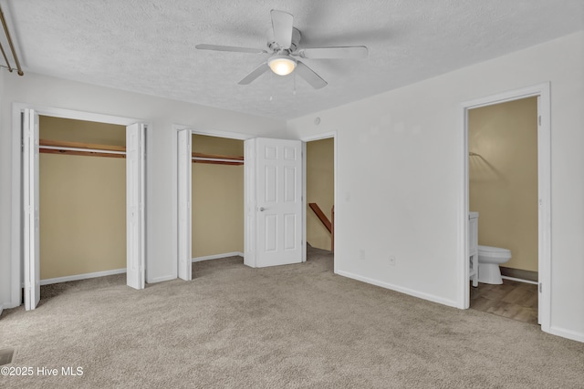 10165 Creekside Dr SE Apt 1, Leland, NC 28451 - unfurnished bedroom with multiple closets, carpet floors, a textured ceiling, ensuite bathroom, and baseboards