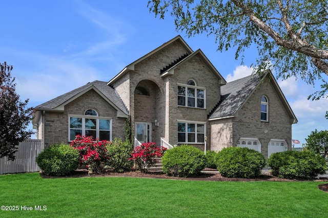 traditional-style house with brick siding, a garage, fence, and a front yard