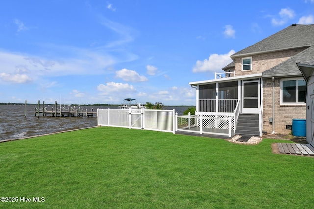 view of yard with a sunroom, a gate, fence, and a water view