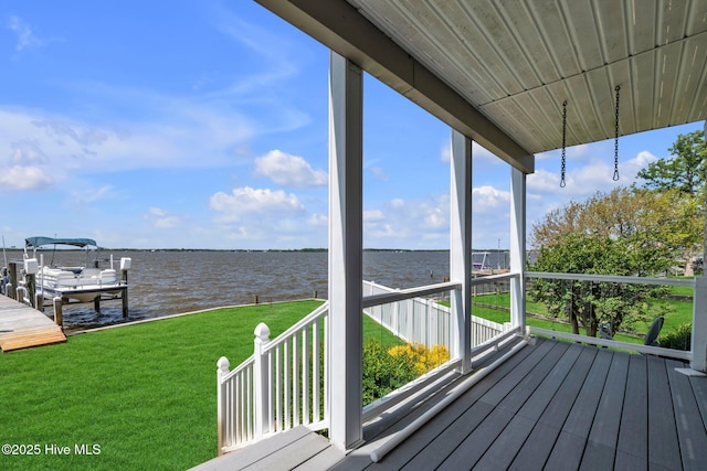 deck with a water view, boat lift, a yard, and a dock