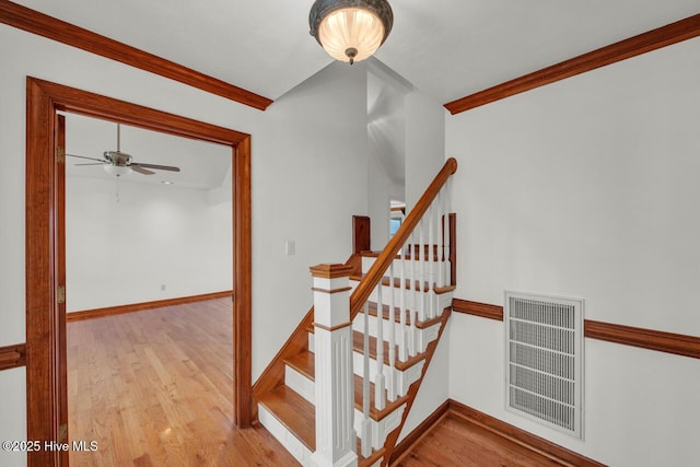 stairway featuring ceiling fan, visible vents, crown molding, wood finished floors, and baseboards