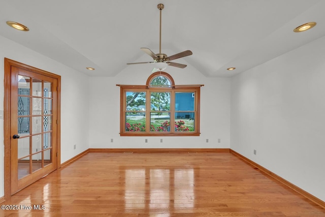 spare room with baseboards, ceiling fan, light wood finished floors, and lofted ceiling