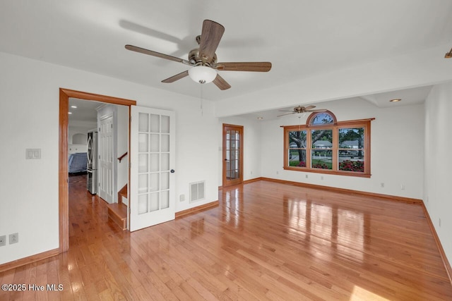 spare room with ceiling fan, visible vents, baseboards, and light wood-type flooring