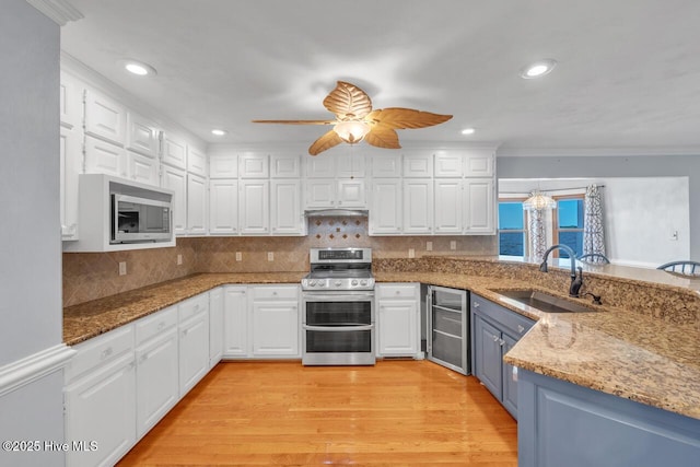 kitchen featuring a sink, a peninsula, white cabinets, and stainless steel appliances