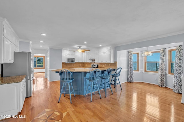kitchen with a breakfast bar area, stainless steel appliances, recessed lighting, white cabinetry, and backsplash