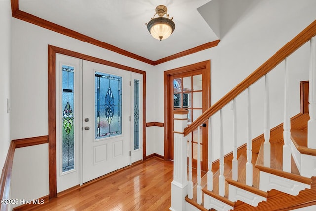 entryway featuring wood-type flooring, stairs, crown molding, and baseboards