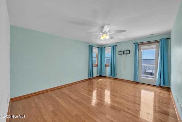 unfurnished room featuring a ceiling fan, baseboards, and wood finished floors