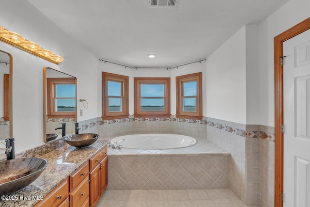 bathroom featuring tile patterned flooring, a sink, a bath, and double vanity