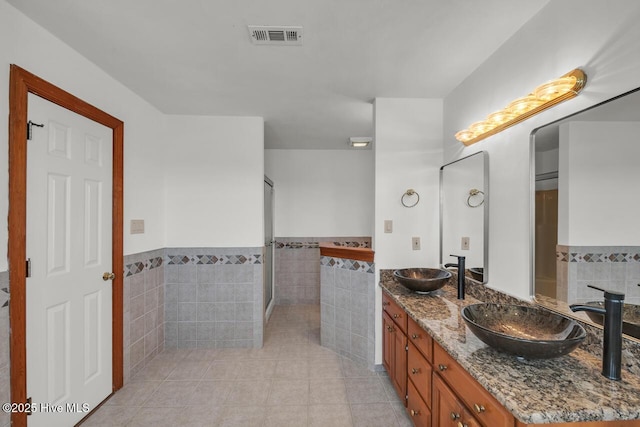 bathroom featuring tile walls, visible vents, a sink, and tile patterned flooring